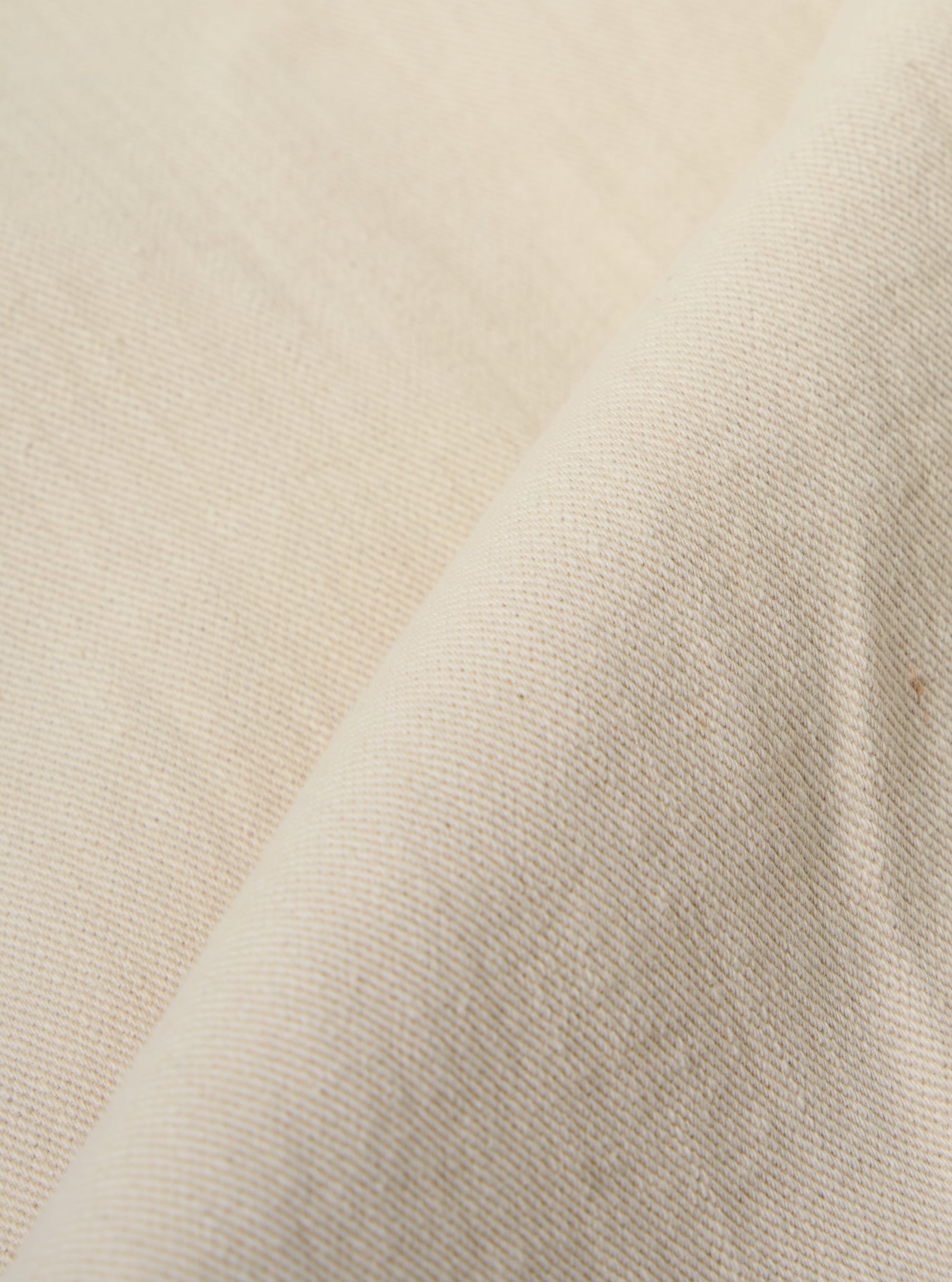 A close-up fabric swatch of the Ecru Koko Cotlin Smock Overshirt highlights the light ecru color and the textured, slubby weave of the cotton-linen blend fabric.