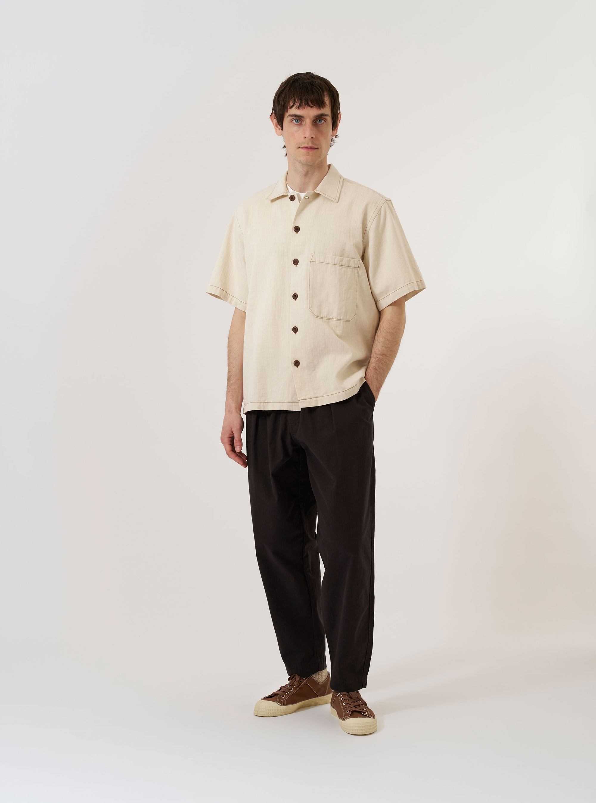 The Ecru Koko Cotlin S/S Fatigue Shirt is shown as a flat lay against a plain white background. The short-sleeved shirt features a central button-down front, a structured collar, and two prominent patch pockets on the chest. The ecru-colored fabric highlights a distinct cotton-linen weave texture.