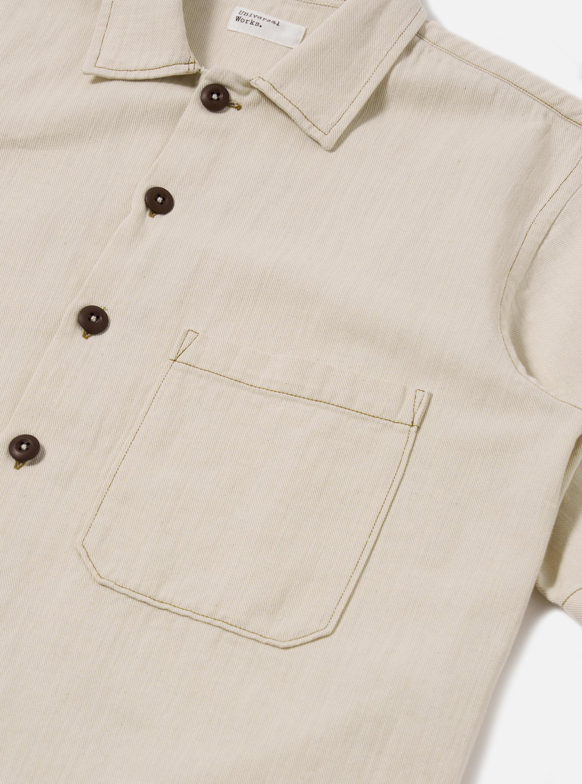 The Ecru Koko Cotlin S/S Fatigue Shirt is shown in a detail view as a flat lay against a plain white background. The image highlights the textured ecru cotton-linen fabric and the construction of the functional front patch pockets and button-down closure.