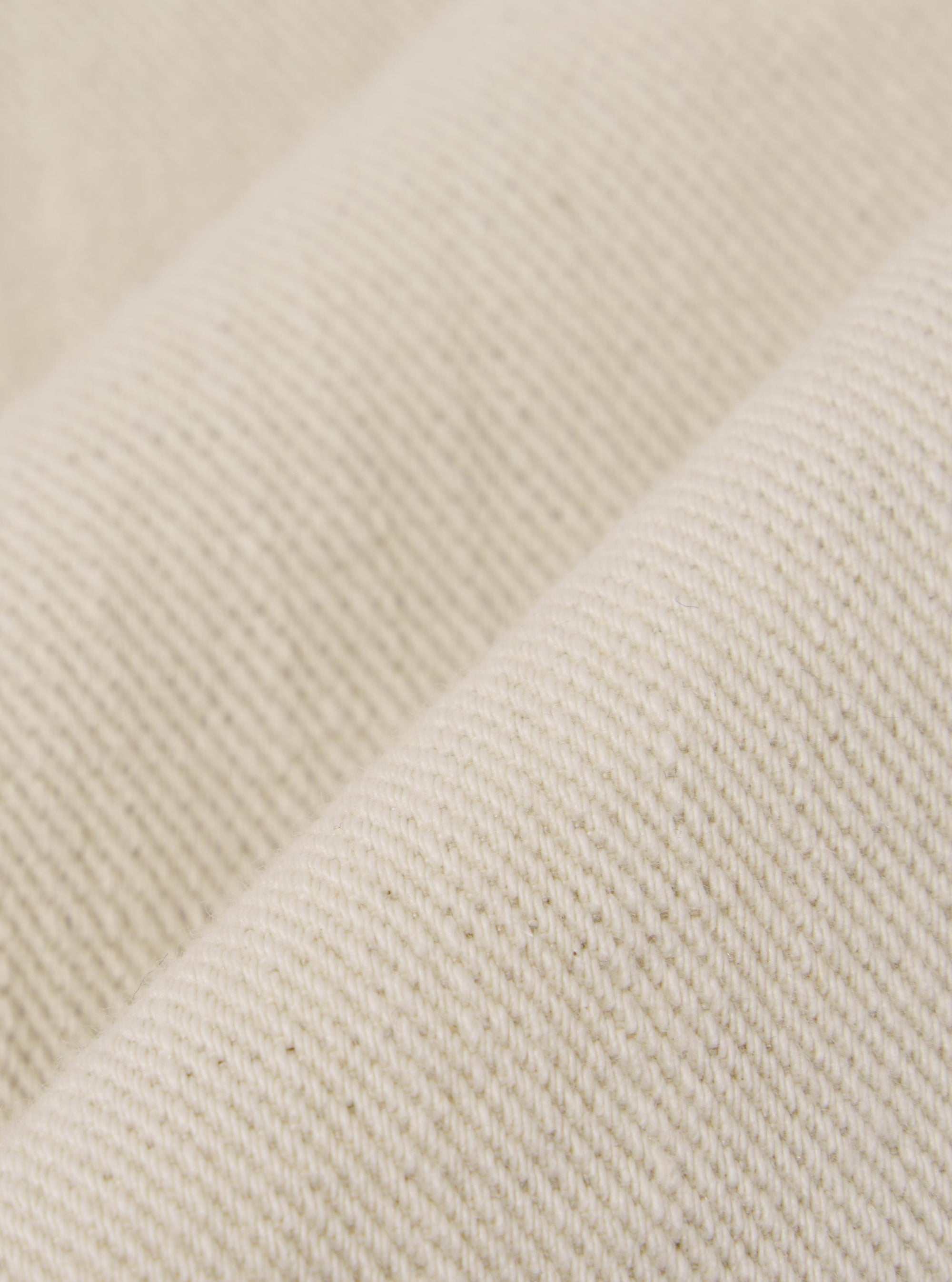 A close-up fabric swatch of the Ecru Koko Cotlin S/S Fatigue Shirt highlights the light cream, ecru color and the textured weave of the cotton-linen material. The fabric detail is shown against a neutral background, with no model or mannequin present in the image.