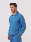 A model wears the Washed Indigo Recycled Herringbone Smock Overshirt against a plain, neutral background. The overshirt is a pullover style featuring a collar, a partial front button placket, and a visible herringbone weave in a washed indigo blue. The garment is shown with a relaxed fit as the model stands facing the camera.
