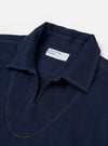 The Indigo Recycled Herringbone Smock Overshirt is shown from the back as a flat lay against a plain white background. The image highlights the garment's textured herringbone weave in a deep indigo blue, featuring a simple, straight-cut back panel and a clean hemline.