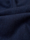 The Indigo Recycled Herringbone Smock Overshirt is shown in a detail view as a flat lay against a plain white background. The image highlights the textured herringbone weave of the indigo blue fabric and the construction of the large front patch pockets and hem.