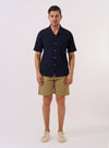 The Navy Seersucker Shirting Road Shirt is shown as a flat lay against a plain white background. The shirt features a camp collar, a central button-down front with tonal buttons, and a single chest patch pocket on the left side. The fabric has a distinct puckered seersucker texture in a deep navy blue.