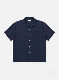 The Navy Seersucker Shirting Road Shirt is shown as a flat lay against a plain white background. The shirt features a camp collar, a central button-down front with tonal buttons, a single chest patch pocket, and short sleeves. The dark navy fabric has a distinct puckered seersucker texture.