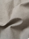 The Grey Izumi Cotton Dockside is shown from the back as a flat lay against a white background. The image highlights the back yoke with small pleats and the relaxed, boxy fit of the overshirt. The lightweight cotton fabric features a visible marled texture with slubbed threads.