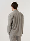 A model is wearing the Grey Izumi Cotton Dockside, shown from the back against a plain white background. The overshirt features a relaxed fit, a straight hem, and a simple back panel. The grey Izumi cotton fabric has a distinct textured appearance. No mannequin is present in the image.