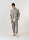 The Grey Izumi Cotton Dockside is shown as a flat lay against a plain white background. The overshirt features a classic collar, a central button-down front, and two large patch pockets at the waist. The fabric is a light grey cotton with a visible textured weave.