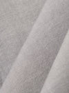 A close-up fabric swatch of the Grey Izumi Cotton S/S Fatigue Shirt highlights the grey color and the specific texture of the cotton material. The fabric fills the frame, providing a detailed view of the weave.