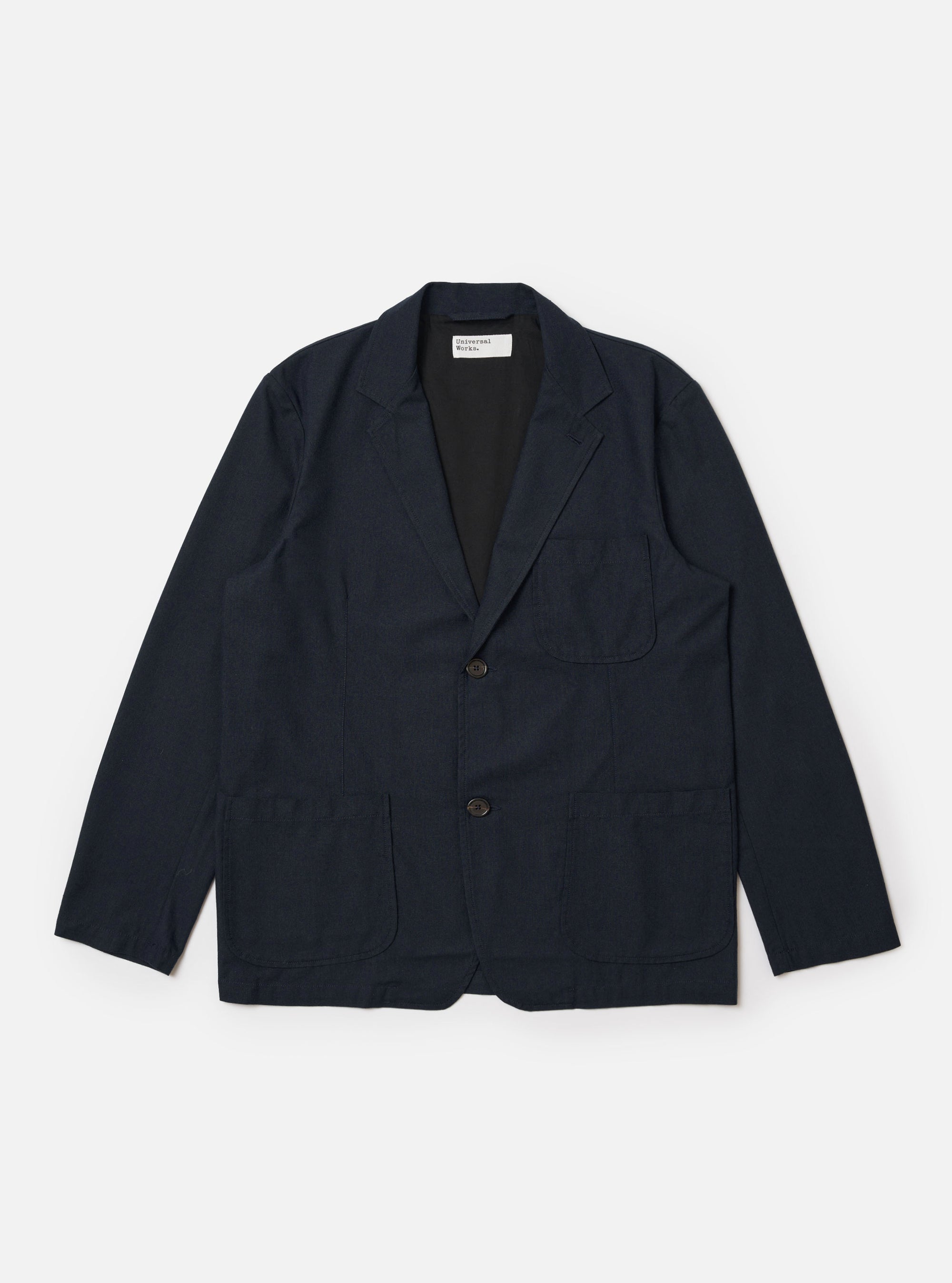 The Navy Valencia Cotton Two Button Jacket is displayed as a flat lay against a plain white background. The jacket features notched lapels, a two-button front closure, and two large patch pockets at the waist. The dark navy fabric has a smooth, structured appearance.
