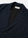 The Navy Valencia Cotton Two Button Jacket is shown from the back as a flat lay against a plain white background. The image highlights the clean construction of the rear panel and the textured navy blue cotton-blend fabric. The jacket features two vents at the hem and visible stitching along the seams and shoulders.