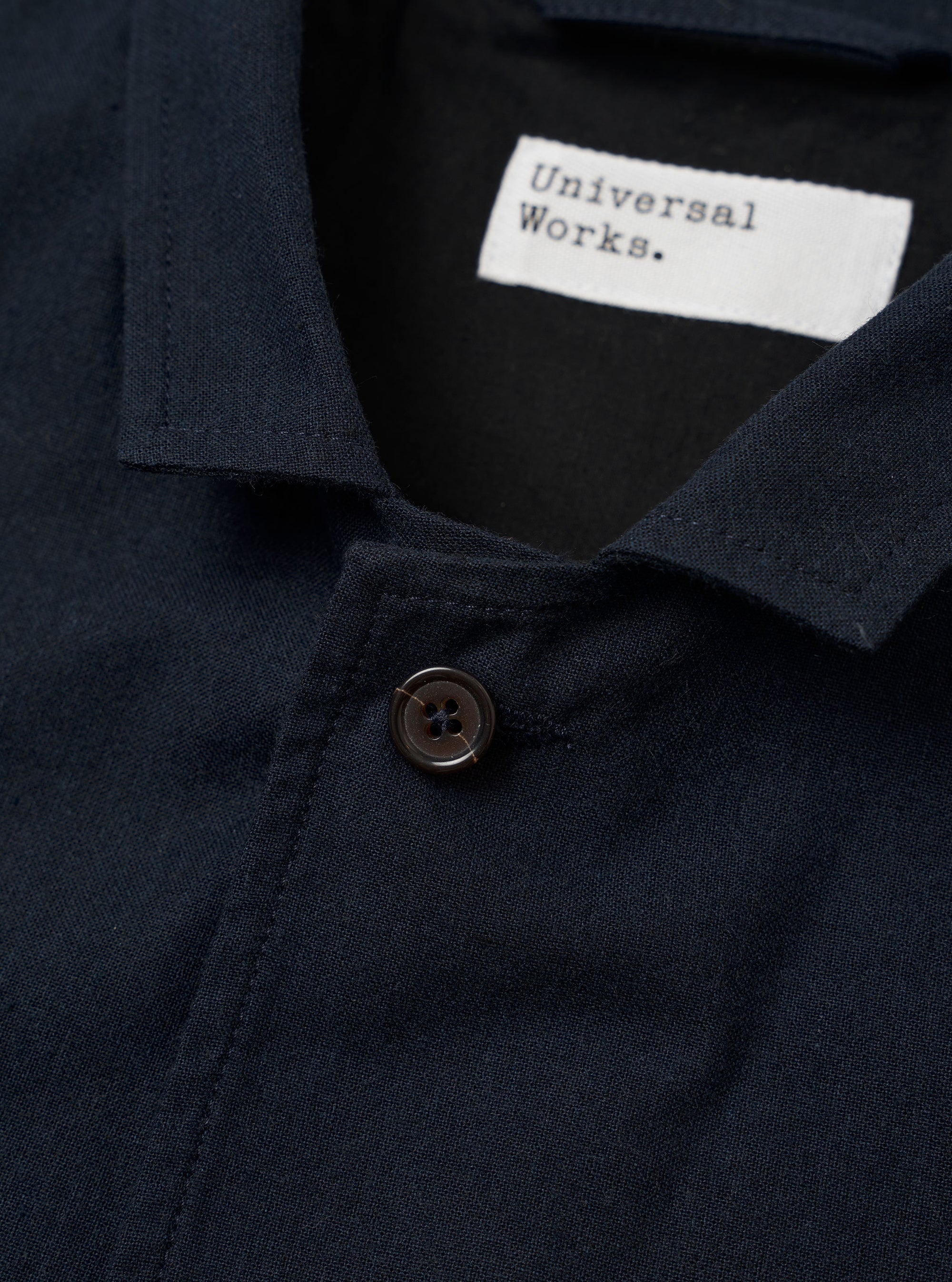 The Navy Valencia Cotton Two Button Jacket is shown from the back as a flat lay against a plain white background. The image highlights the clean construction of the garment's rear, featuring two side vents at the hem and a two-piece sleeve design. The fabric is a dark navy blue with a smooth finish.