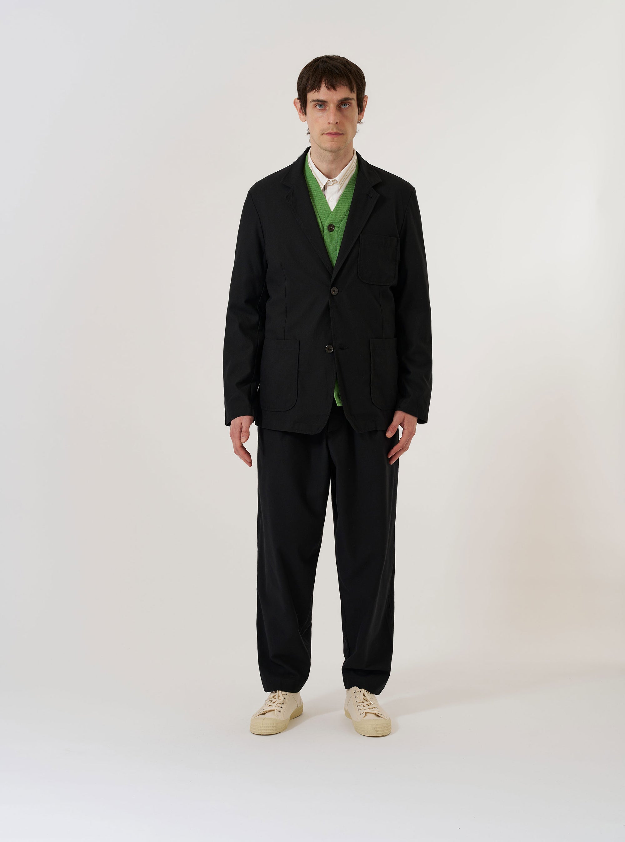 The Black Valencia Cotton Two Button Jacket is shown as a flat lay against a white background. The jacket features a two-button front closure, notch lapels, a single chest patch pocket, and two large patch pockets at the waist. The fabric is a solid black cotton blend with a smooth, structured finish.