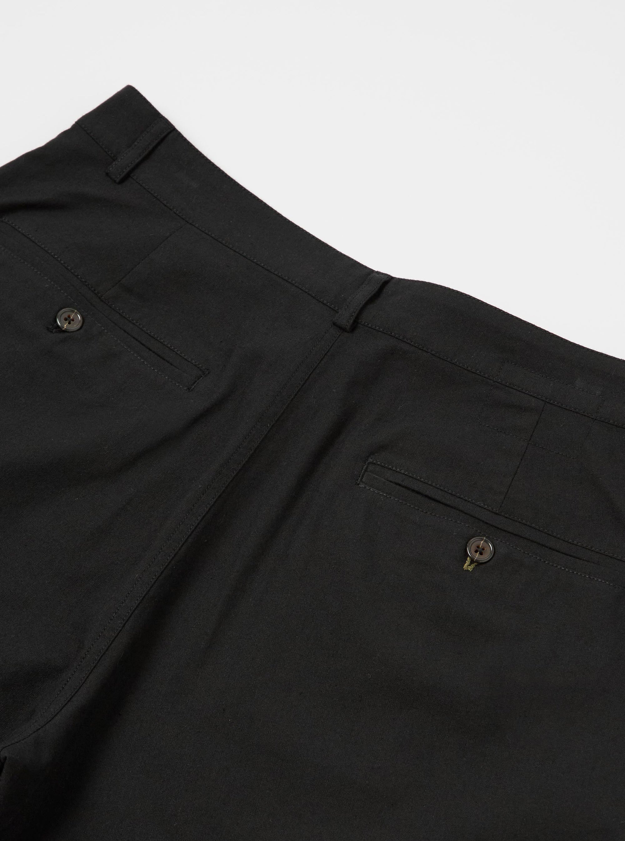 The Black Valencia Cotton Military Chino is shown from a rear angle as a flat lay against a plain white background. The image highlights the two rear patch pockets, one with a button-down flap, and the clean construction of the straight-leg design. The black fabric has a subtle, textured appearance.