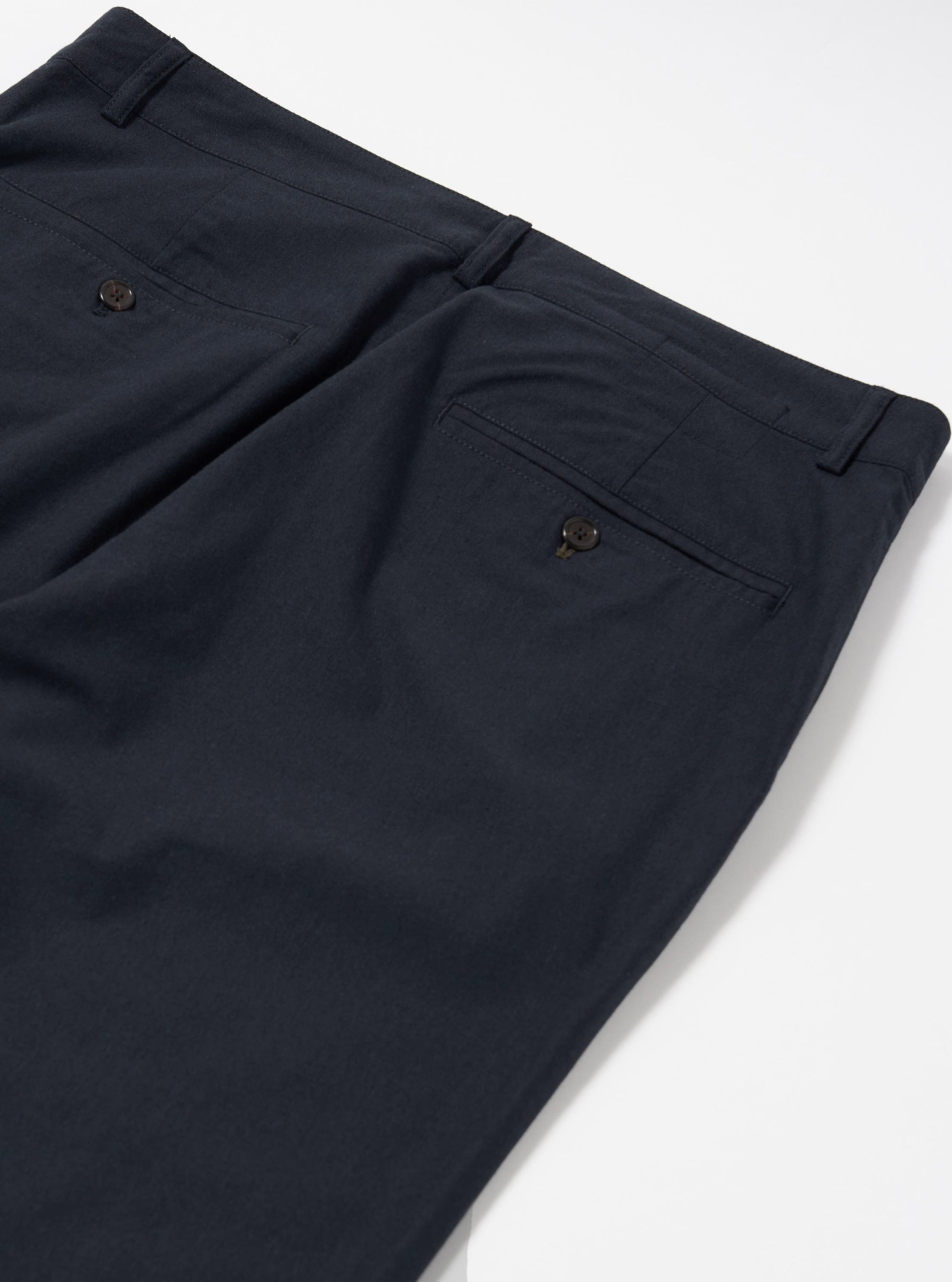 The Navy Valencia Cotton Military Chino is shown from a rear angle as a flat lay against a plain white background. The image highlights the two rear patch pockets, one with a button-down flap, and the clean stitching along the waistband and central seam. The dark navy fabric has a visible textured quality.
