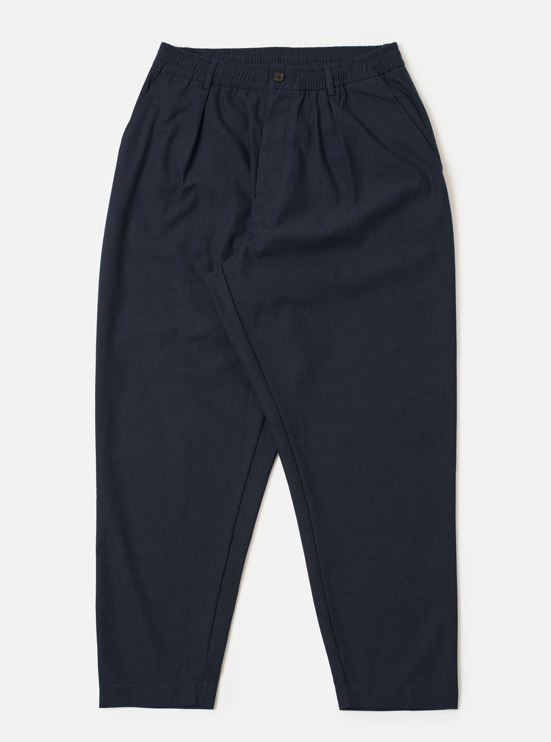 The Navy Valencia Cotton Pleated Track Pant is shown as a flat lay against a plain white background. The trousers feature an elasticated waistband with an external drawstring, a single pleat at the front, and two side pockets. The fabric is a dark navy blue with a smooth, clean finish.