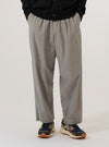 A model wears the Grey Izumi Cotton Oxford Pant, standing against a plain white background. The trousers feature a wide-leg, loose fit with distinct front pleats and an adjustable drawstring at the waist. The garment is made from a light grey cotton fabric with a visible texture.