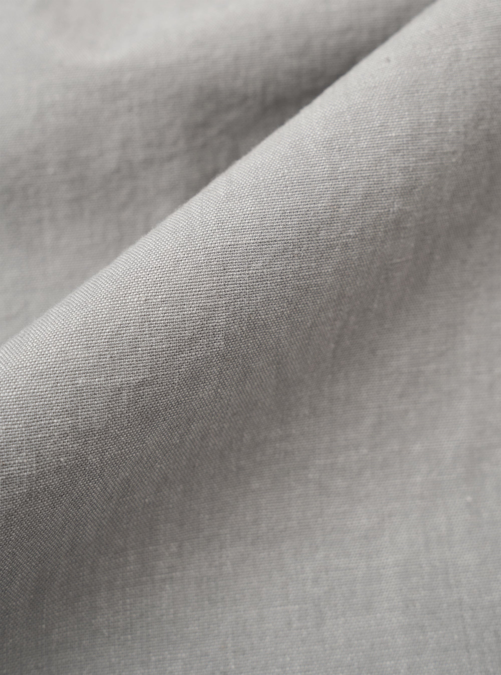 A close-up swatch image of the Grey Izumi Cotton Oxford Pant fabric displays a grey color with a visible textile weave. The texture of the cotton material is clearly shown, filling the entire frame.