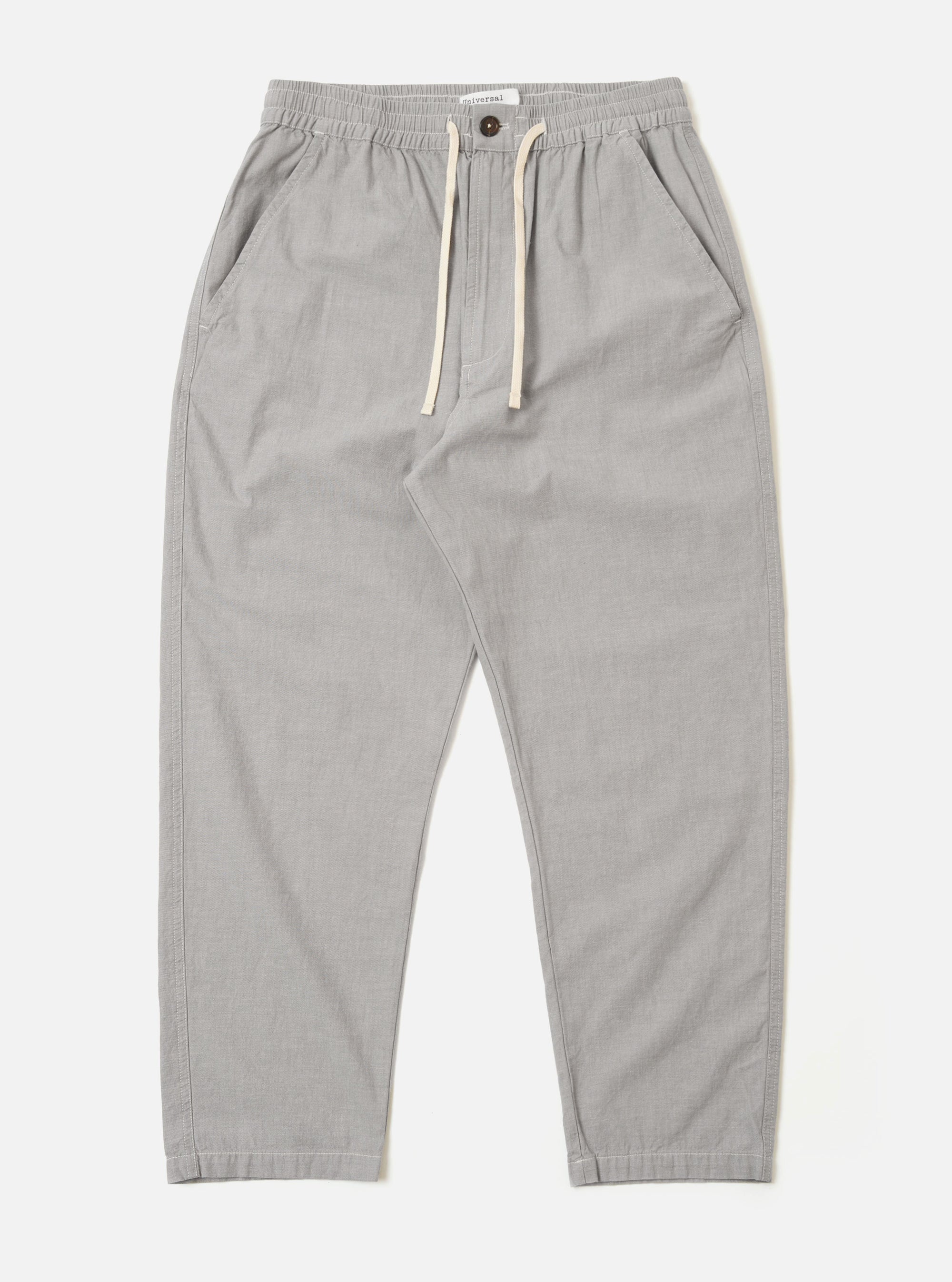 The Grey Izumi Cotton Hi Water Trouser is shown as a flat lay against a white background. The trousers feature a relaxed fit, a cropped length, and a drawstring waist with a visible white cord. The grey cotton fabric has a subtle, textured appearance.