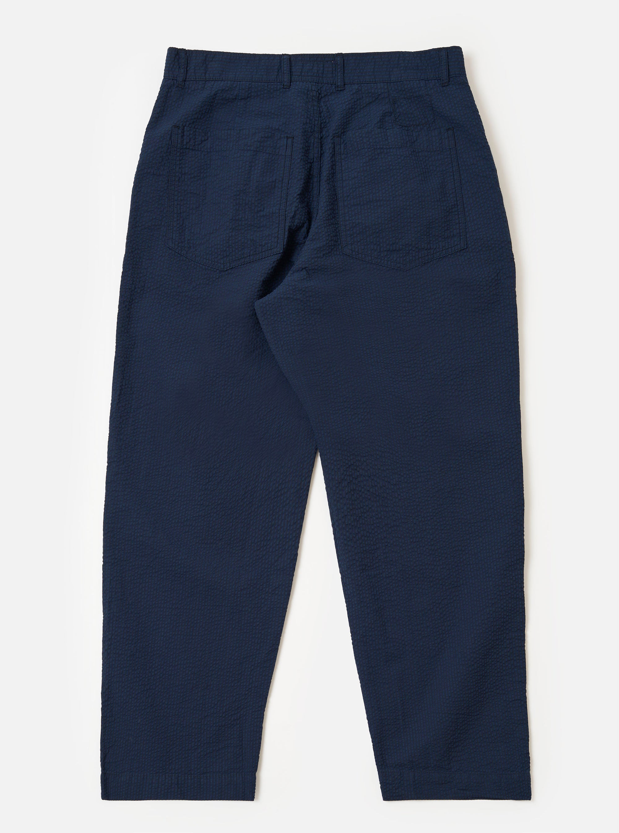 The Navy Derby Stripe Duke Pant is shown from the back as a flat lay against a plain white background. The trousers feature a loose, wide-leg fit and are made from a navy blue cotton fabric with thin, vertical white stripes. Visible details include a single rear patch pocket on the right side and a clean, straight hem.