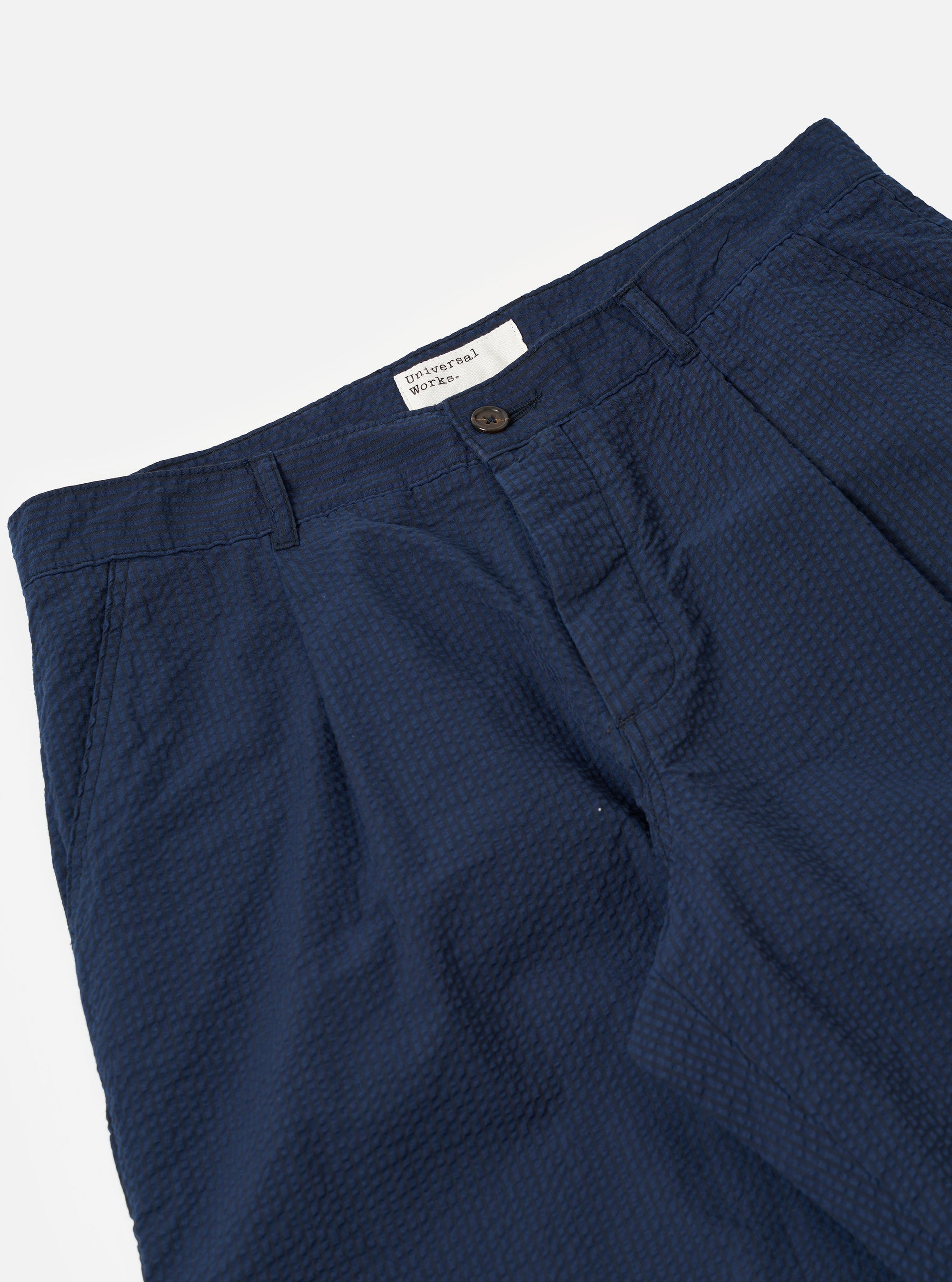 The Navy Derby Stripe Duke Pant is shown from the back as a flat lay against a plain white background. The image highlights the two rear patch pockets, a straight hem, and the vertical derby stripe pattern in navy and white.