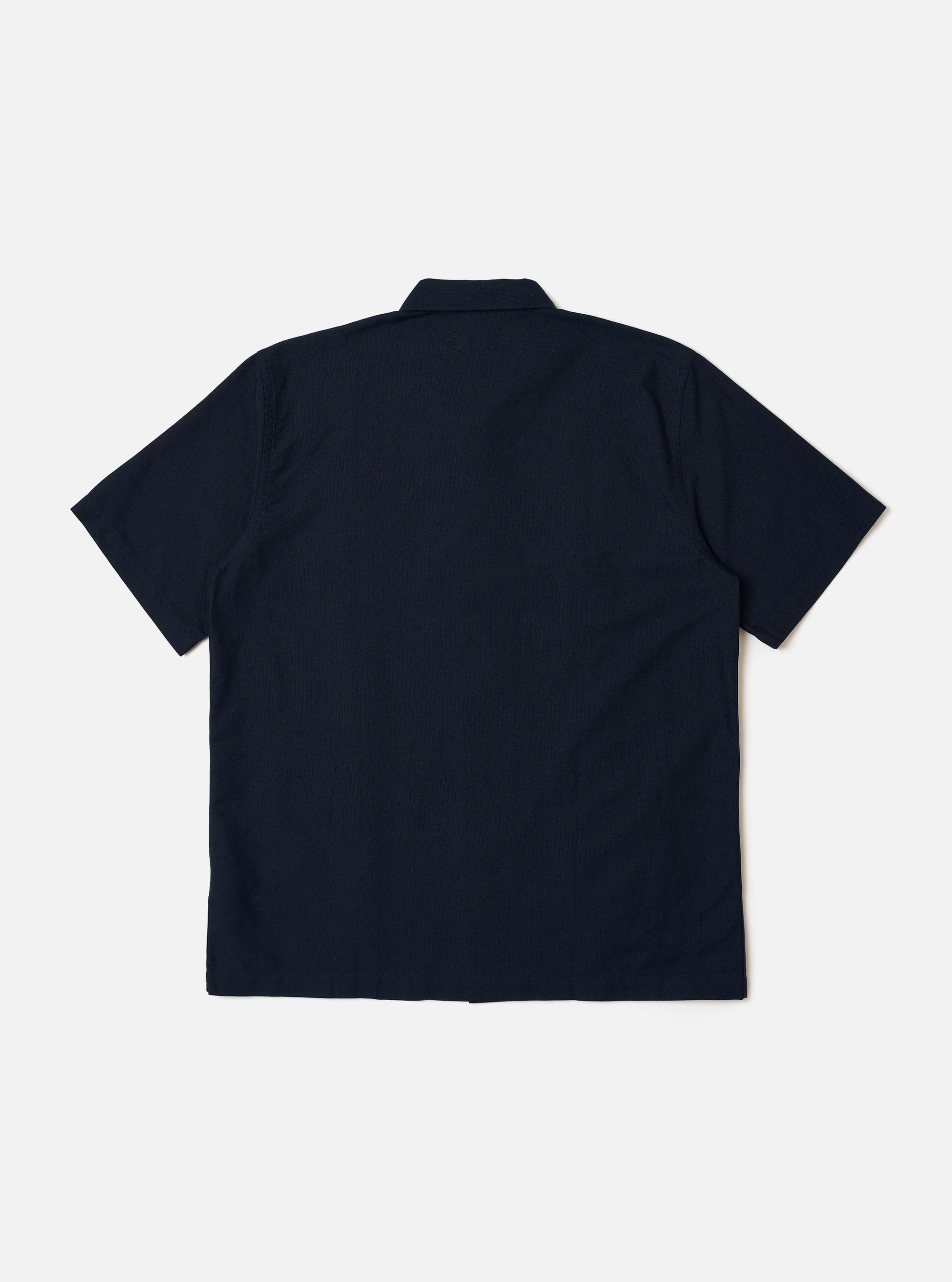 The Navy Classic Oxford Tropicana Shirt is shown from the back as a flat lay against a white background. The image highlights the relaxed fit, one-piece collar, and short, loose sleeves. The hem is slightly curved and longer at the back with small side splits.