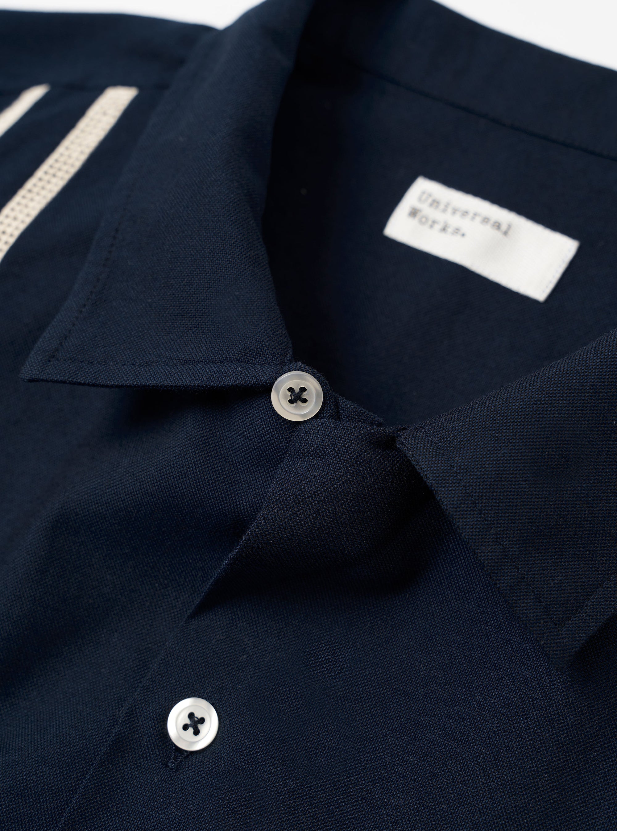 The Navy Classic Oxford Tropicana Shirt is displayed as a flat lay against a plain white background. The image shows the back of the shirt, highlighting its clean construction, simple yoke, and straight hem. The deep navy blue cotton fabric has a visible oxford weave texture.