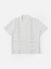 The White Classic Oxford Tropicana Shirt is shown as a flat lay against a white background. The shirt features a one-piece open collar, short loose sleeves, and two large patch pockets located at the lower front hip area. It has a center-front button closure and is made from a textured white Oxford cotton fabric.