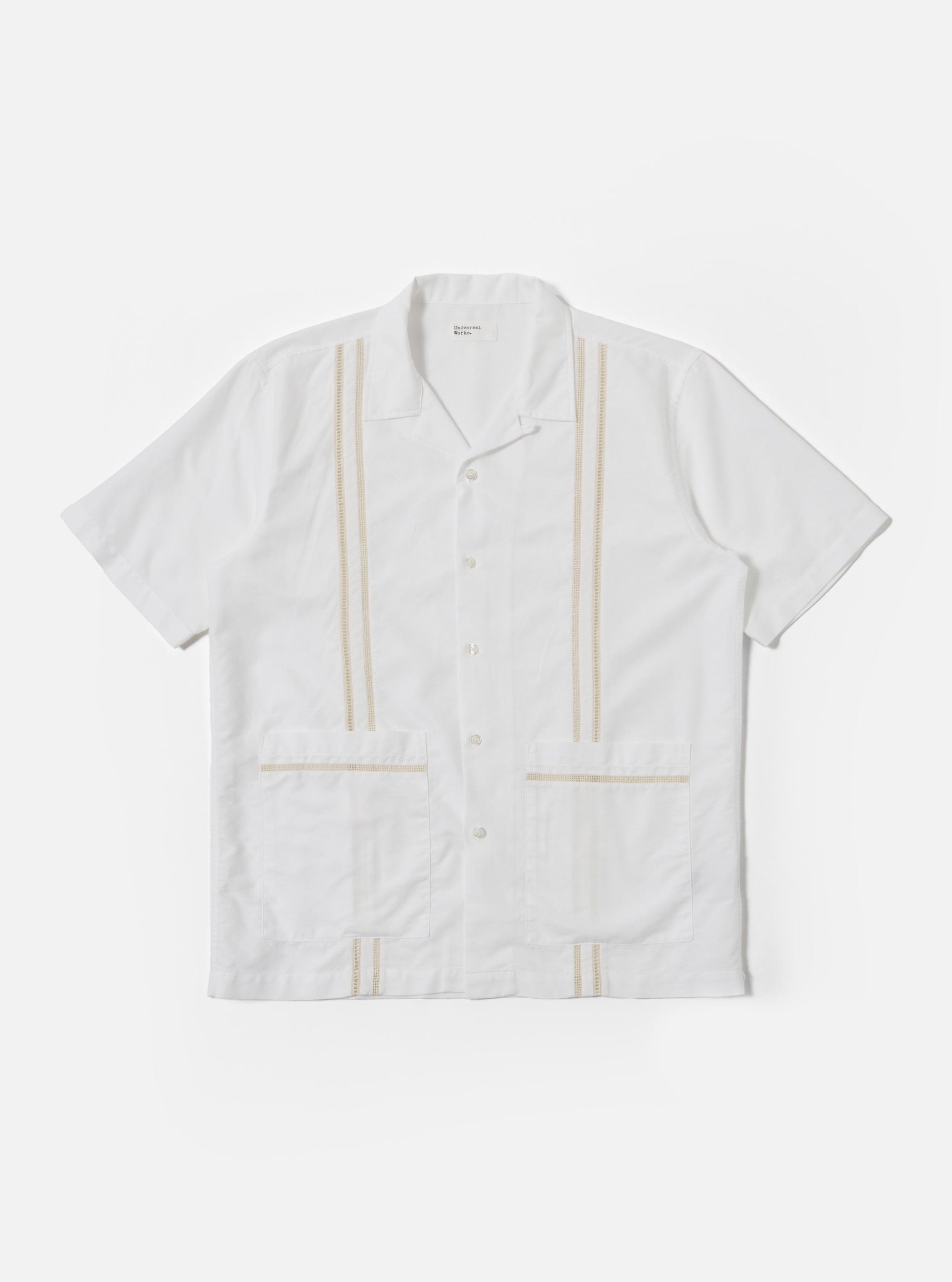 The White Classic Oxford Tropicana Shirt is shown as a flat lay against a white background. The shirt features a one-piece open collar, short loose sleeves, and two large patch pockets located at the lower front hip area. It has a center-front button closure and is made from a textured white Oxford cotton fabric.