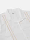 The White Classic Oxford Tropicana Shirt is shown from a back angle, worn by a model against a white background. The image highlights the shirt's short raglan sleeves with a small slit at the cuff and a straight hem. The model has their hands in their trouser pockets, showcasing the shirt's relaxed fit and soft Oxford cotton texture.