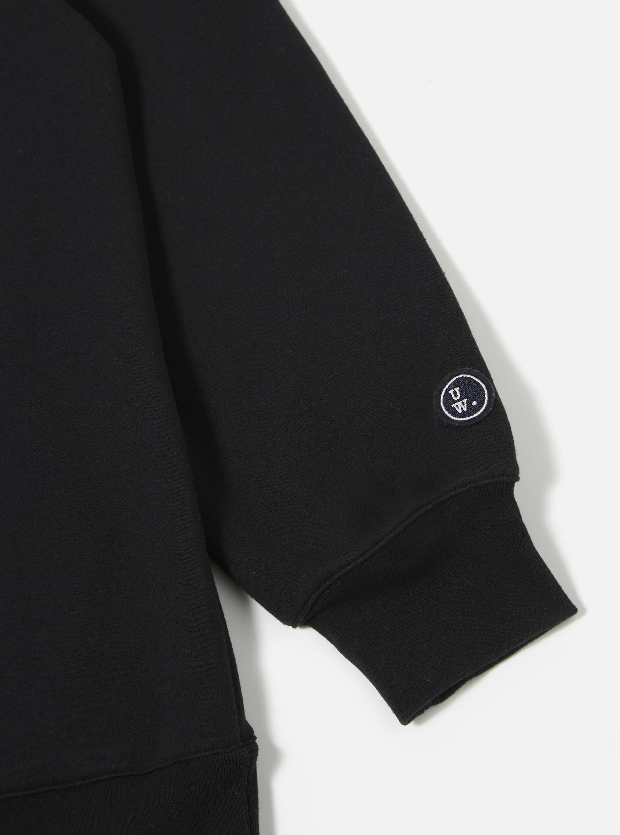The Black Recycled Cotton Blend Jersey Loose Sweatshirt is shown from the back as a flat lay against a plain white background. The image highlights the sweatshirt's relaxed fit, dropped shoulders, and ribbed detailing at the collar, cuffs, and hem. The garment is made from a solid black recycled cotton blend jersey with a smooth finish.