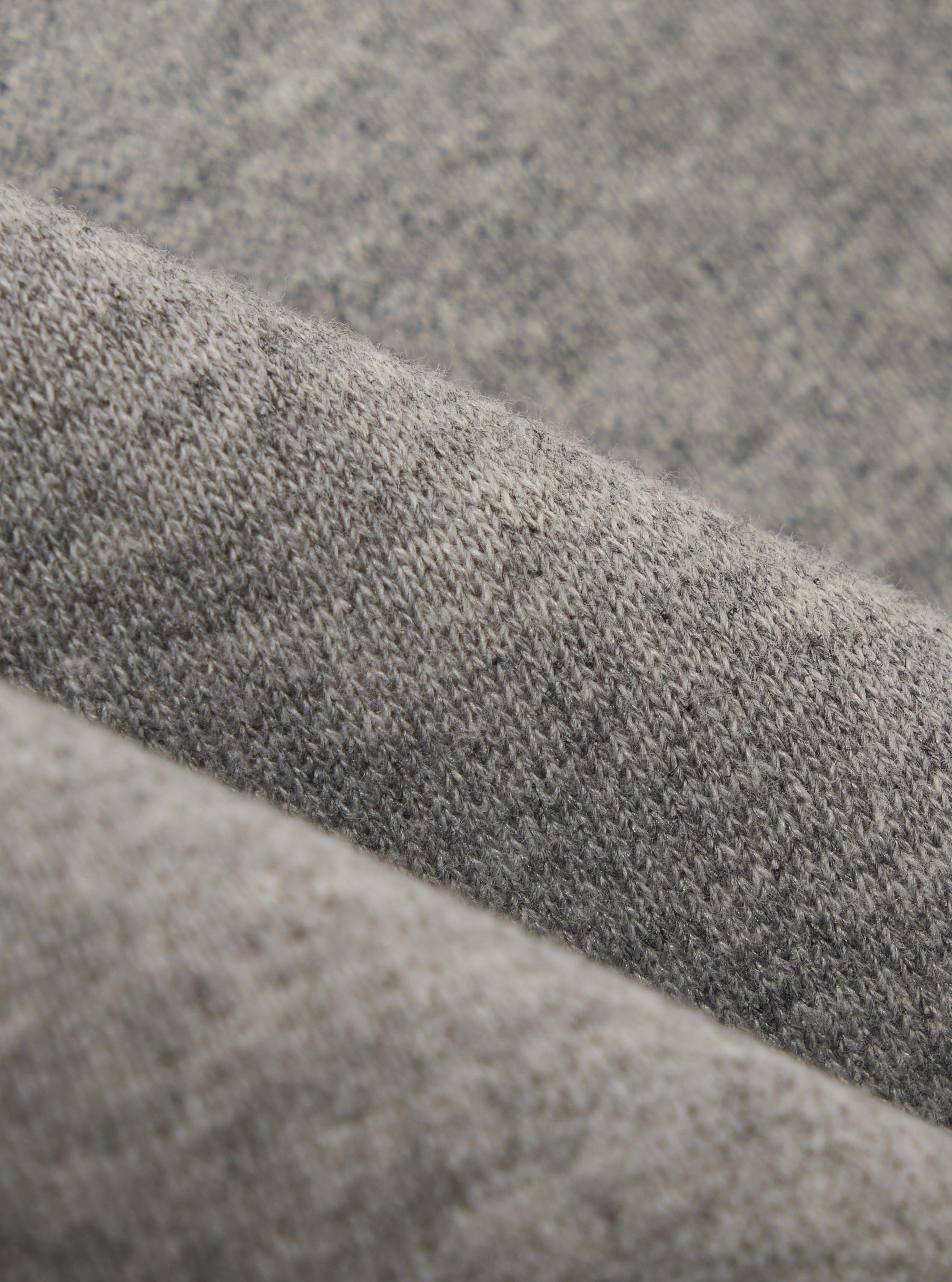 A close-up fabric swatch of the Grey Marl Recycled Cotton Blend Jersey Loose Sweatshirt displays a light grey heathered texture. The image focuses on the soft, knit quality of the recycled cotton blend material, which fills the entire frame.