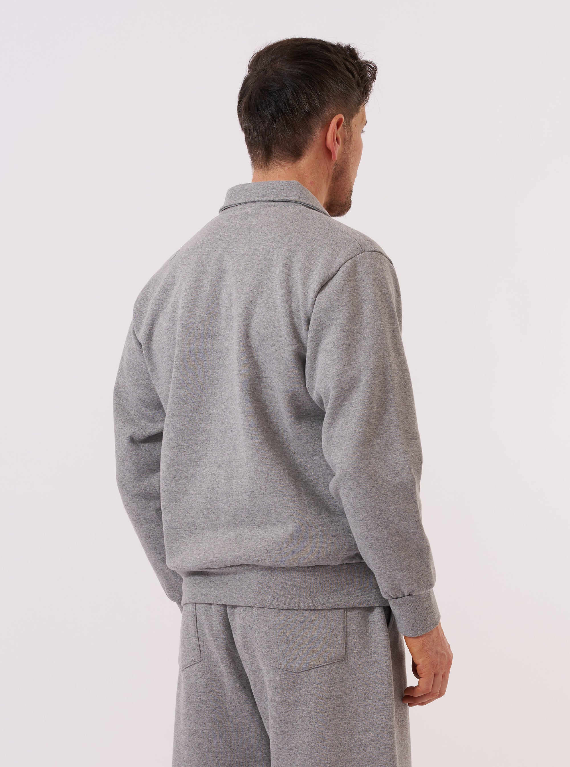 A model wears the Grey Marl Recycled Cotton Blend Jersey Tyler Jacket, shown from the back against a plain white background. The jacket features a relaxed fit with a straight hem, a simple neckline, and visible seam detailing across the shoulders and down the center back. The grey marl fabric has a soft, heathered texture.