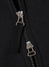 The Black Recycled Cotton Blend Jersey Tyler Jacket is shown in a detail view as a flat lay against a white background. The image highlights the jacket's textured black jersey fabric, a ribbed hem, and a single front patch pocket with a velcro fastening.