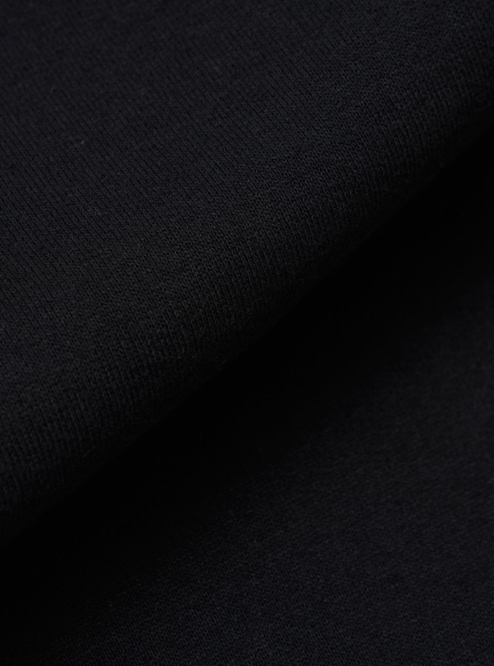 A close-up swatch image of the Black Recycled Cotton Blend Jersey Vacation Short fabric highlights the soft, matte texture of the black jersey knit material. The image provides a detailed view of the fabric's composition and consistent dark color.