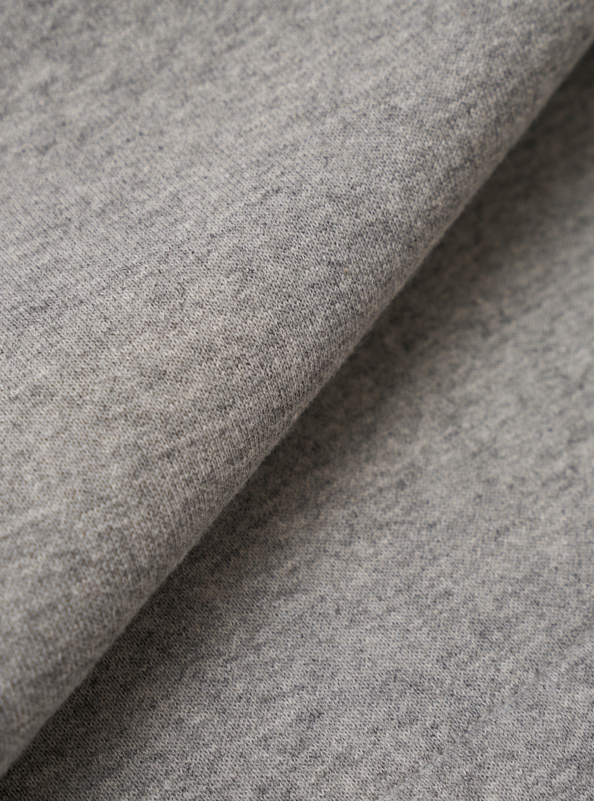 A close-up fabric swatch of the Grey Marl Recycled Cotton Blend Jersey Vacation Short highlights the soft, knitted texture of the material. The fabric features a classic heathered grey marl pattern, showing a blend of light and dark grey tones.