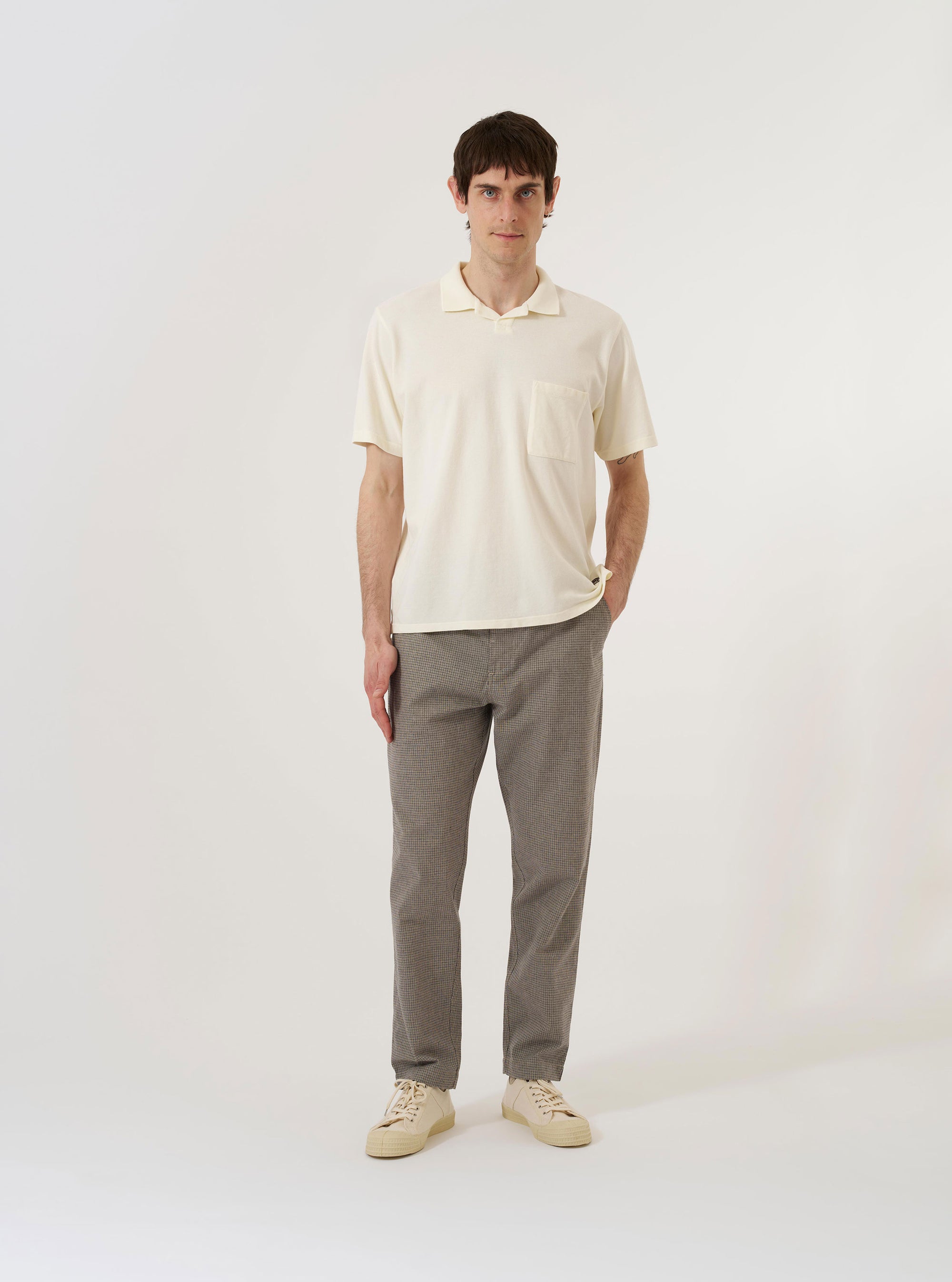 The Ecru Piquet Vacation Polo is shown as a flat lay against a white background. The shirt features an open one-piece collar, a single chest patch pocket, and a straight hem with side vents. The textured cotton piqué fabric is shown in a solid ecru color.