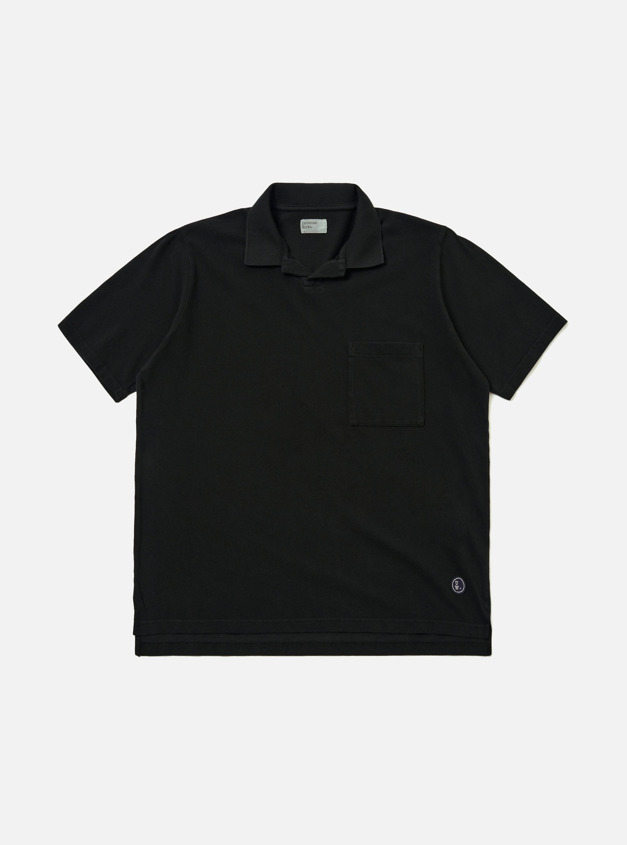 The Black Piquet Vacation Polo is shown as a flat lay against a plain white background. The polo features a single-piece open collar, a short-button placket, and a single patch pocket on the left chest. The black cotton fabric has a visible textured piquet weave.