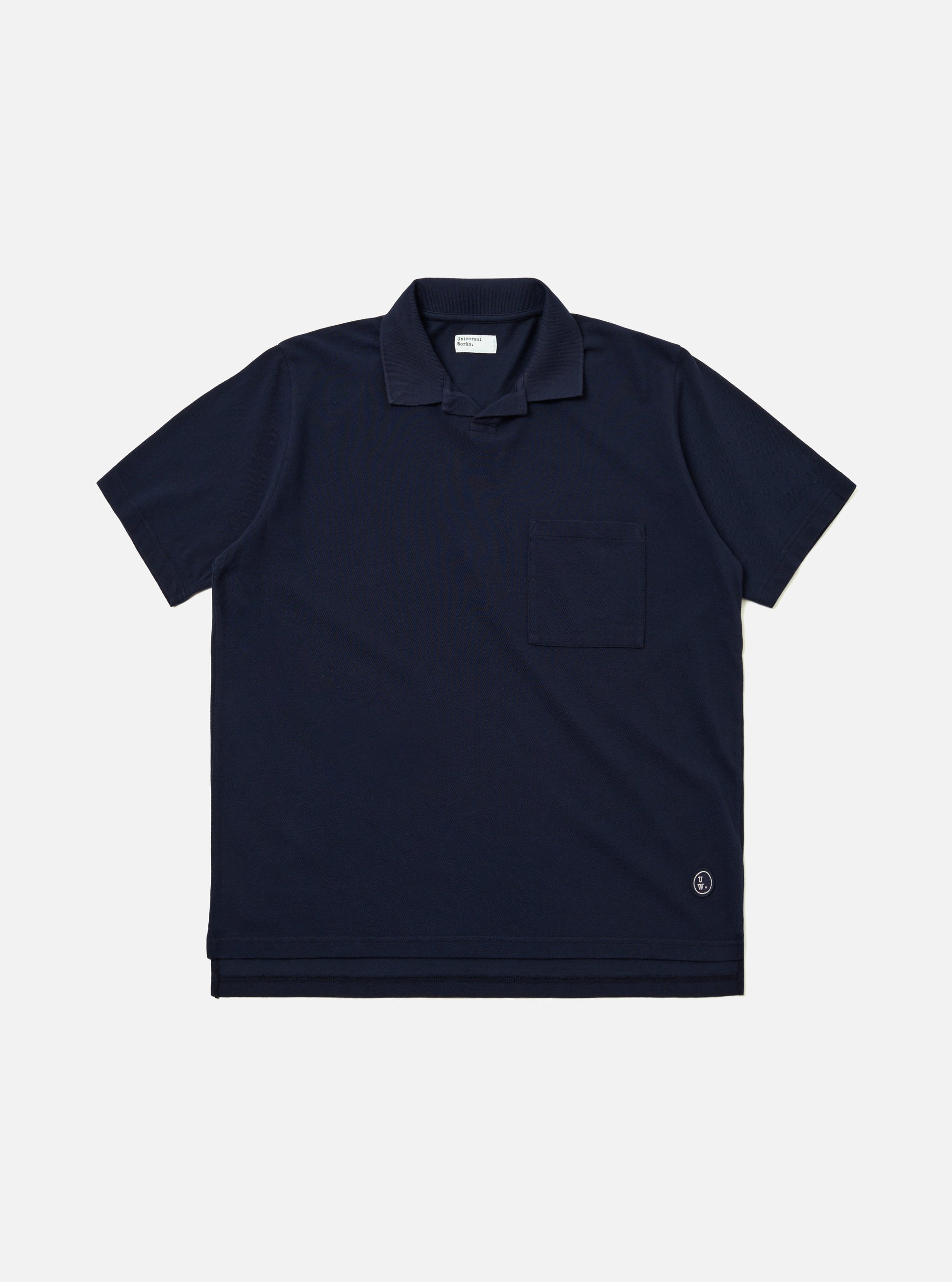 The Bright Navy Piquet Vacation Polo is shown as a flat lay against a white background. The polo features a buttonless open collar, a single patch pocket on the left chest, and a straight hem. The bright navy cotton fabric has a visible textured piquet weave.