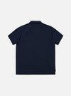 A model wears the Bright Navy Piquet Vacation Polo against a plain, neutral studio background. The polo is made from a textured piquet cotton and features a relaxed open one-piece collar, short sleeves, and a single patch pocket on the left chest. The model is shown from the waist up, highlighting the shirt's regular fit and vibrant navy color.