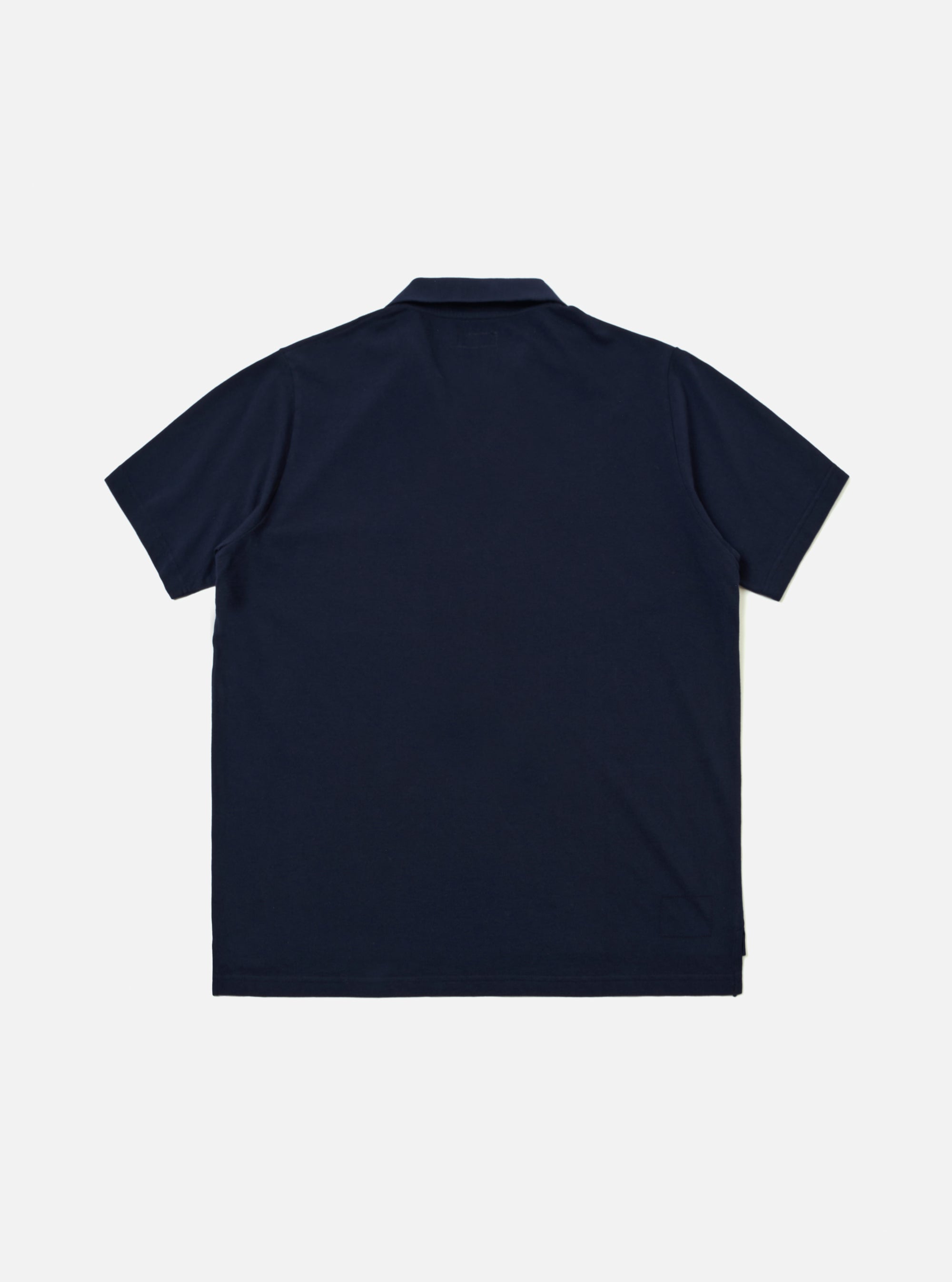 A model wears the Bright Navy Piquet Vacation Polo against a plain, neutral studio background. The polo is made from a textured piquet cotton and features a relaxed open one-piece collar, short sleeves, and a single patch pocket on the left chest. The model is shown from the waist up, highlighting the shirt's regular fit and vibrant navy color.