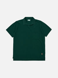 The Green Piquet Vacation Polo is displayed as a flat lay against a plain white background. The shirt features a one-piece collar, a single patch chest pocket, and a short-sleeve construction. The green piquet fabric has a distinct, textured honeycomb-like weave.