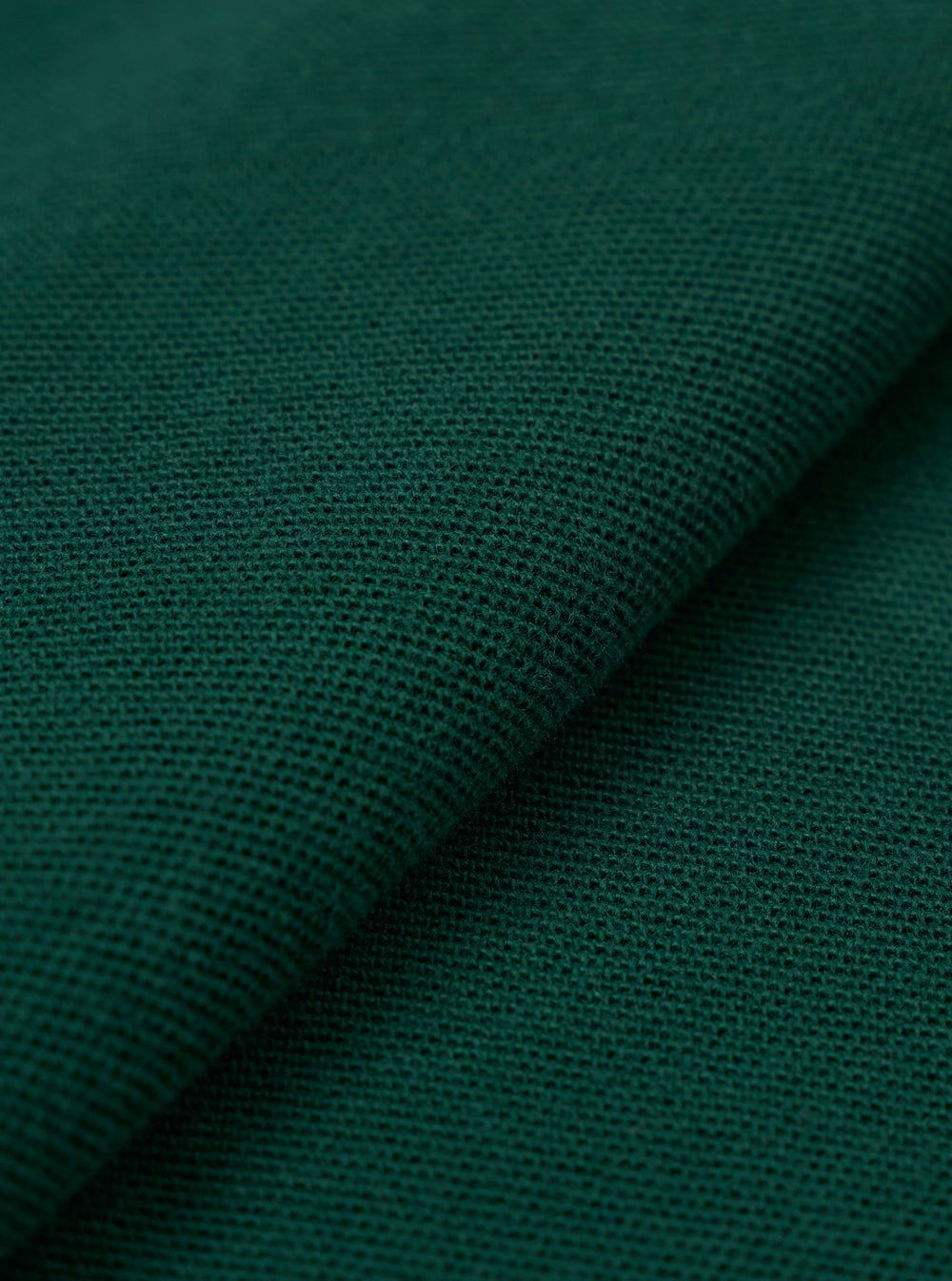 A close-up fabric swatch of the Green Piquet Vacation Polo highlights the textured, breathable weave of the green piquet fabric. The image provides a detailed view of the garment's color and knit construction.