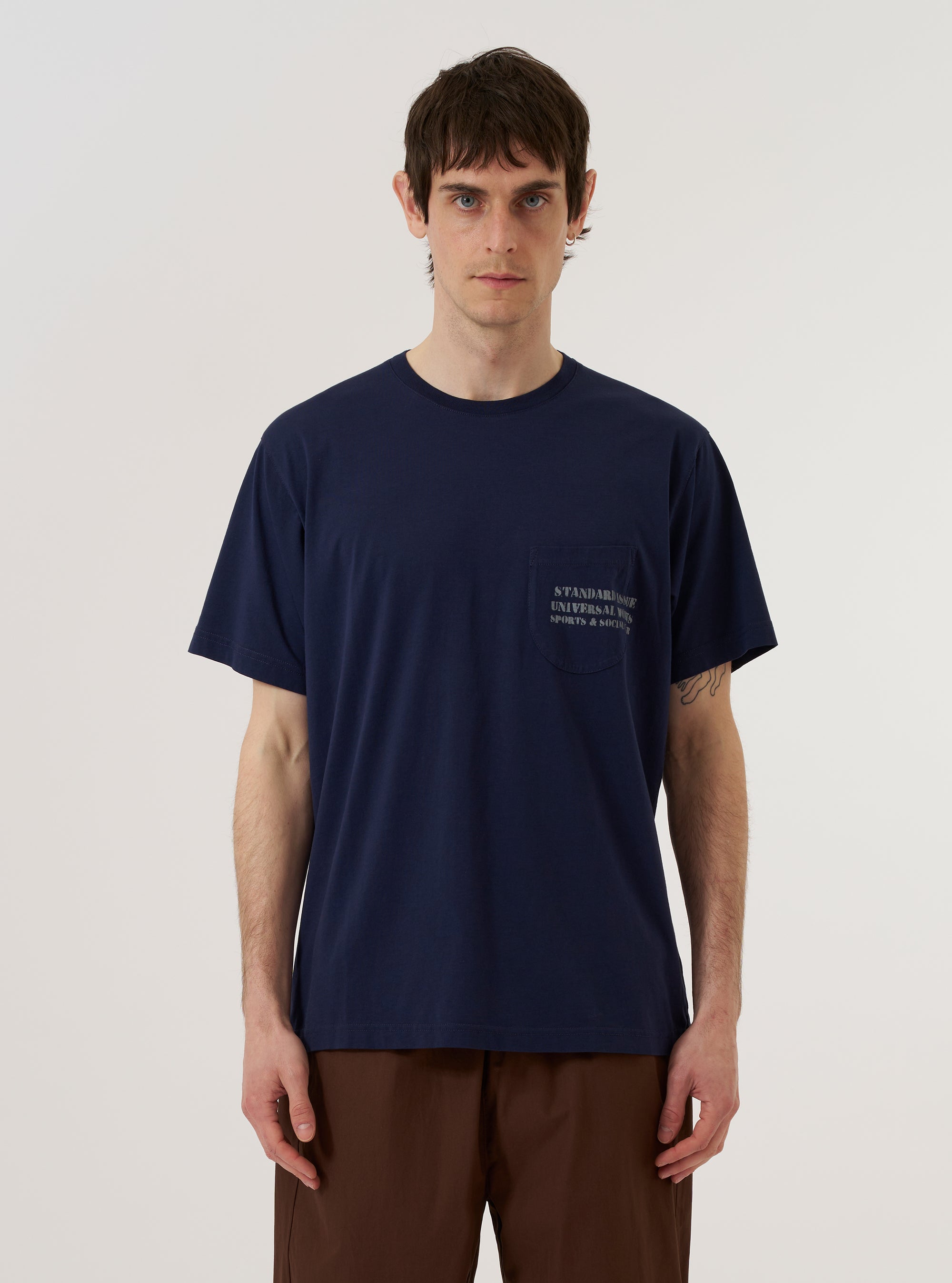 A model wears the Bright Navy Organic Jersey Print Pocket Tee against a plain, light-colored background. The t-shirt features a crew neckline, short sleeves, and a patch pocket on the left chest with a white graphic print. The garment is a vibrant navy blue and is shown from the front in a medium shot.
