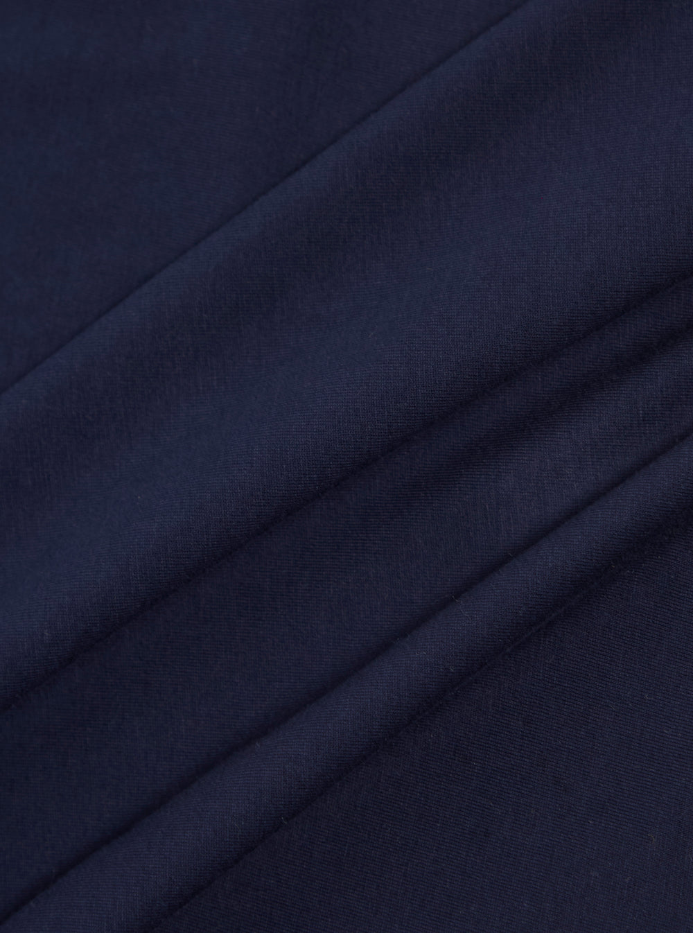 A close-up swatch image of the Bright Navy Organic Jersey Print Pocket Tee fabric highlights the vibrant navy blue color and the soft, fine-knit texture of the organic cotton jersey. The material fills the entire frame, providing a detailed view of the garment's color and construction.