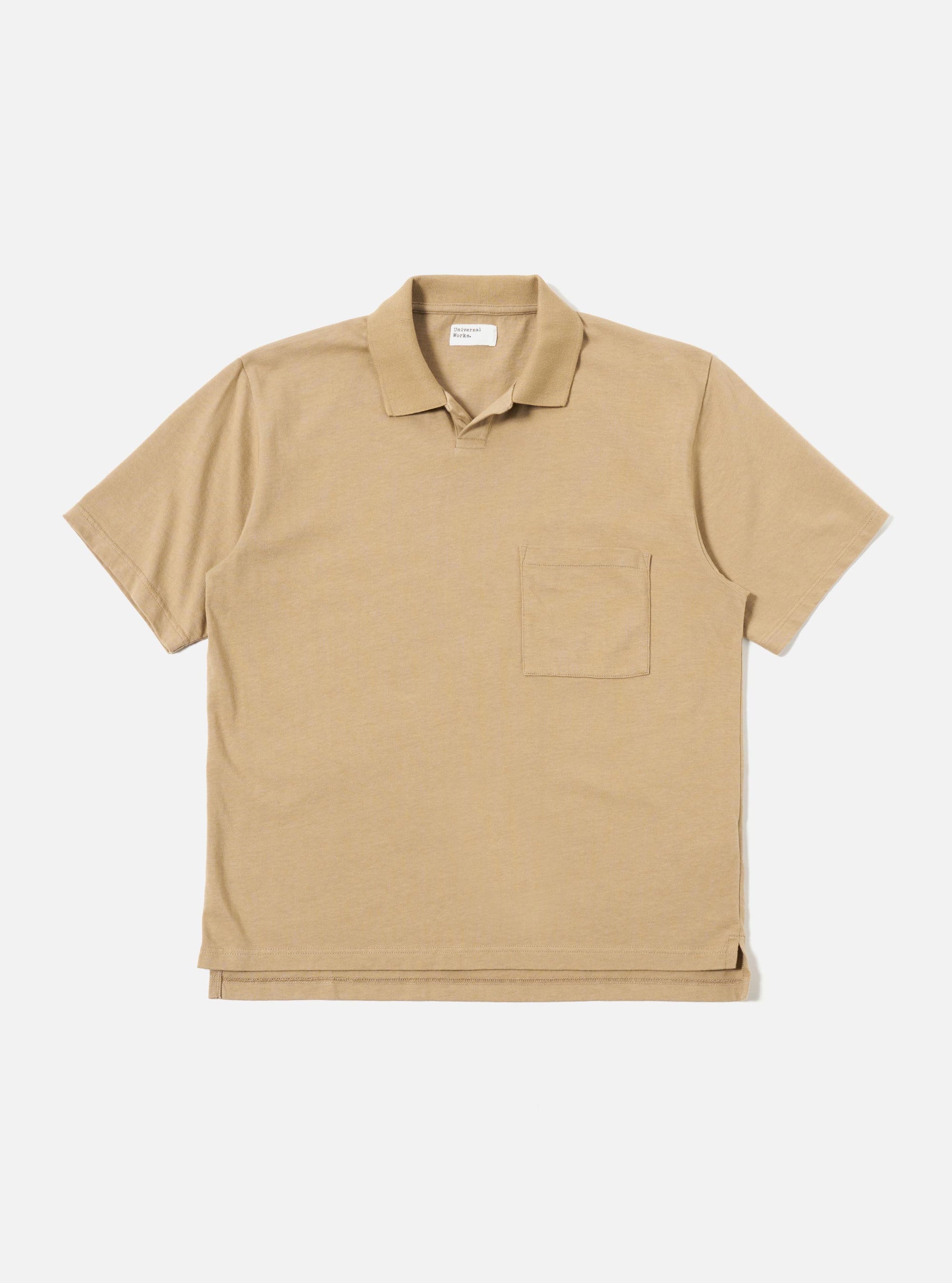 The Sand Rugby Jersey Oversized Vacation Polo is shown as a flat lay against a white background. The polo features an oversized fit, a one-piece collar, a short placket with no fastening, and a single patch pocket on the left chest. The fabric is a heavy-weight rugby jersey in a neutral sand color.