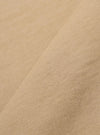 A close-up fabric swatch of the Sand Rugby Jersey Oversized Vacation Polo highlights the sand-colored organic cotton jersey material and its soft, knit texture. The fabric fills the frame, providing a detailed view of the garment's color.