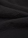 A close-up swatch image of the Black Merida Seersucker Military Chino fabric highlights the garment's black color and the distinct puckered texture of the cotton seersucker material. The image focuses entirely on the textile detail, providing a clear view of the fabric's weave.