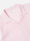The Pink Lily Stripe Road Shirt is shown from the back as a flat lay against a white background. The shirt features vertical stripes in pink and white, a straight hem, and a back yoke with a central box pleat. The short sleeves are visible, and