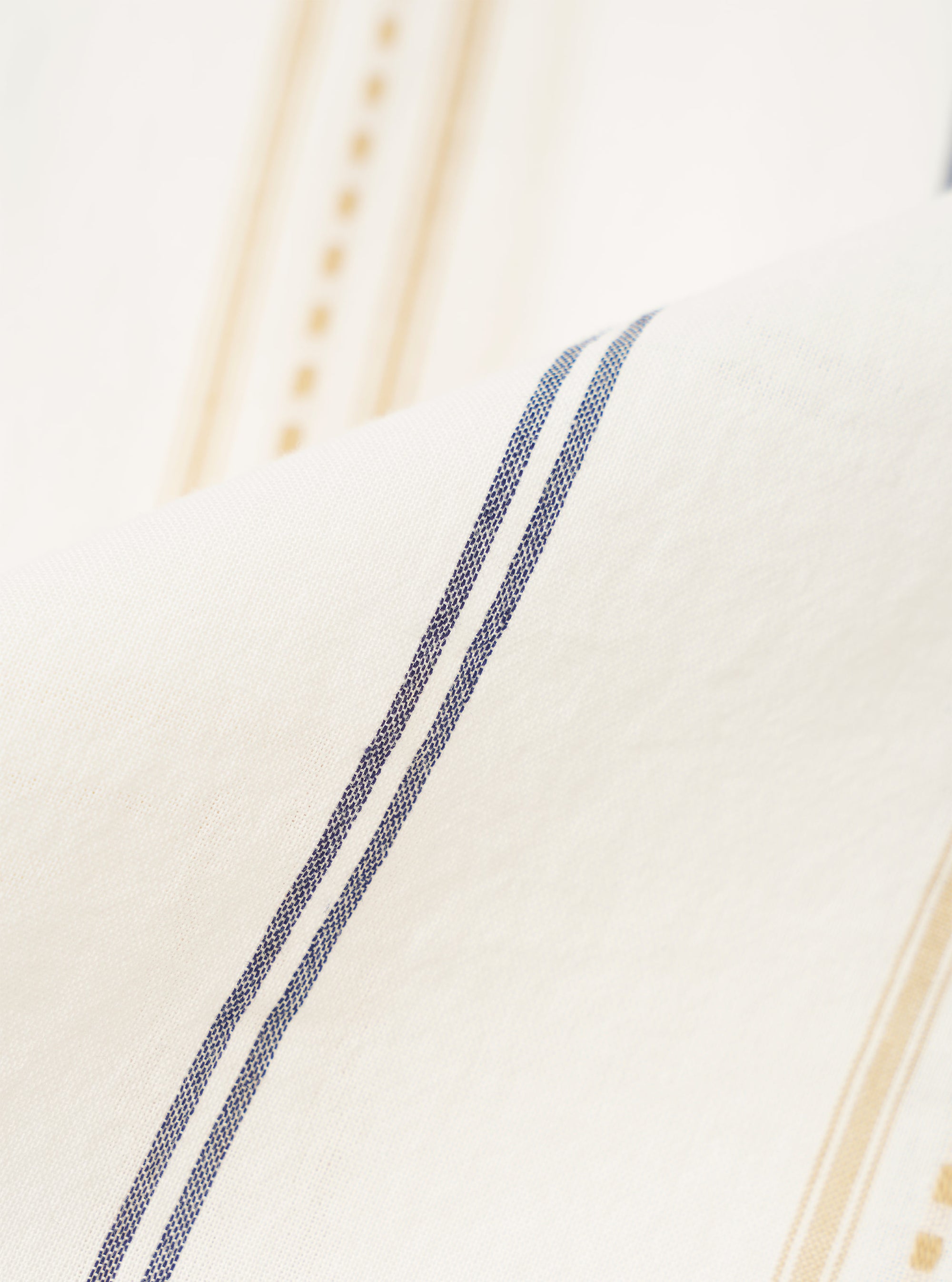A close-up fabric swatch of the Ecru/Navy/Sand Hendrix Stripe Road Shirt shows the vertical stripe pattern in shades of cream, dark navy, and tan. The cotton fabric has a visible weave and the textured stripes run parallel to each other.